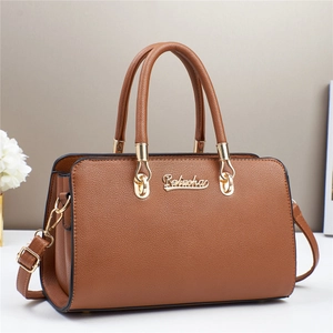 Détail latéral d'un sac bandoulière en similicuir marron avec grain litchi et bijoux dorés