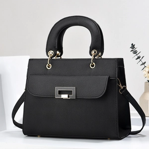 Detailed view of black litchi texture on a stylish women handbag with gold metal clasp