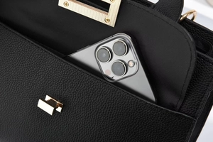 Detail view of black lychee leather crossbody bag with gold buckle and front phone pocket
