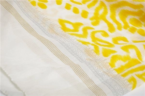 Macro shot of lightweight wave pattern fabric with yellow print and golden line detail