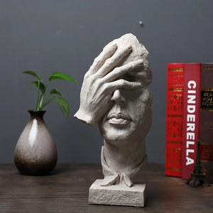 Detail of beige abstract sculpture showing hand covering eyes with stone texture finish