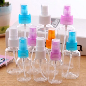 Set of twelve empty clear plastic spray bottles with multi-colored caps on a wooden surface
