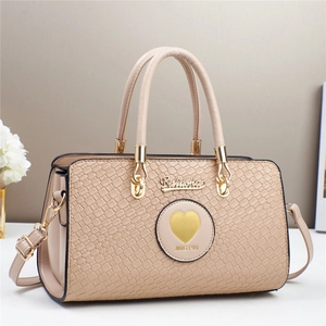Close-up of beige faux crocodile texture and gold heart hardware on an elegant handbag