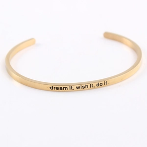Macro shot of gold stainless steel mantra bracelet with dream it wish it do it engraving