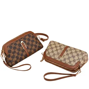 Detail view of monogram printed handbags with golden metal buckle and leather wrist strap