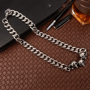 Silver skull Cuban link necklace on brown leather desk mat with a business style