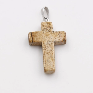 Macro detail of natural stone cross pendant with brown marble texture and silver bail