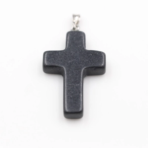 Macro detail of a cross pendant made of polished black natural stone with silver bail