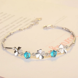 Silver s925 clover bracelet with blue zircon stones on a beige paper background
