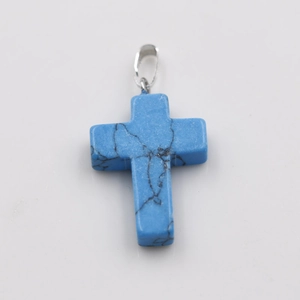 Close-up of blue turquoise cross pendant with natural black veins and silver metal bail
