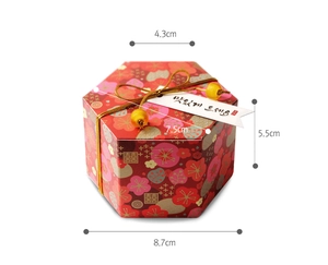 Detail of red hexagonal wedding favor box with floral patterns and gold cord size specs
