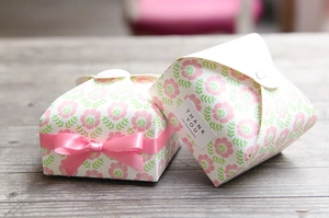 Close-up of paper gift box with pink floral patterns and matching satin ribbon