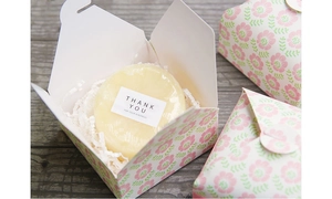 Close-up of floral gift box with soap and a thank you label on wood background