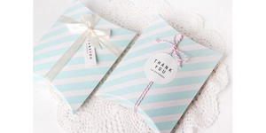 Detail of light blue striped pillow gift boxes with ribbons and Thank You tags on lace