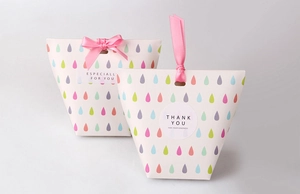 Close-up of cream gift boxes with colorful teardrop prints and pink ribbon bows