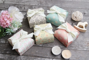 Detailed view of patterned gift boxes with ribbon bows on a wooden surface with flowers