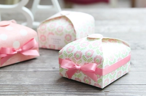 Detailed view of pink floral and polka dot gift boxes with ribbons on a wooden surface