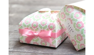 Floral paper gift boxes with pink ribbon and thank you label on wood surface
