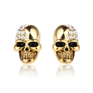 Golden skull stud earrings with white crystals shown with a mirror reflection