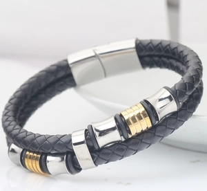 Macro shot of double-layer black braided leather bracelet with gold and silver metal clasps