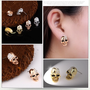 Detail view of vintage gold skull stud earrings with sparkling rhinestones on model