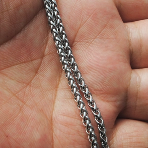 Primer plano macro de una cadena de acero inoxidable plateada sobre una palma