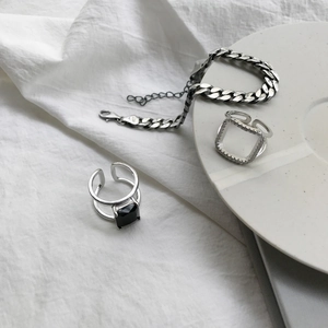 S925 sterling silver cuban chain bracelet and square zircon rings on white fabric