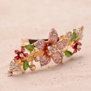 Macro detail of golden metal hair clip with hand-painted enamel flowers and rhinestones