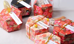 Detailed view of hexagonal paper gift boxes with gold floral patterns in pink and black