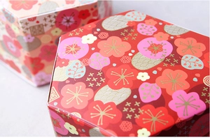 Close-up of hexagonal paper wedding favor boxes with gold plum blossom and cloud patterns