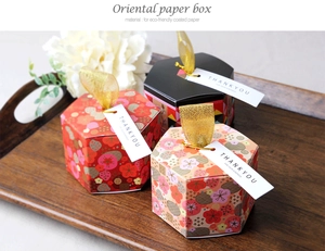Detail of hexagonal paper gift boxes with gold ribbons and thank you tags in three patterns