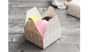 Detailed view of floral paper gift box with pink flowers and three colorful macarons