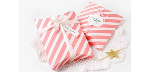 Detailed view of pink striped pillow gift boxes with elegant ribbon and thank you tags