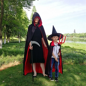 Adult and child wearing reversible red and black hooded capes with Halloween props