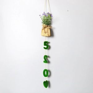 Hanging artificial plant detail featuring yellow burlap bag with love text and floral accents