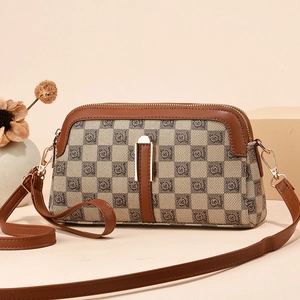 Classic checkered crossbody bag with brown leather trim on a warm minimalist background