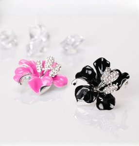 Close-up of pink and black enamel rose brooches with sparkling white crystal centers