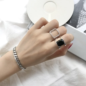 Close-up of hand wearing silver Cuban chain bracelet and geometric zircon rings
