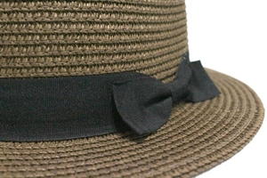 Detail of the dark brown straw hat showing the black grosgrain ribbon and side bow tie