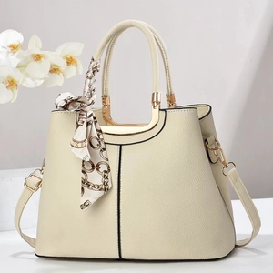 Close-up of cream leather stitching details and elegant silk scarf on the handbag