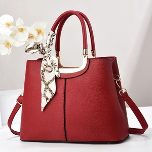 Elegant red pebbled leather handbag with gold metal hardware and silk scarf decoration