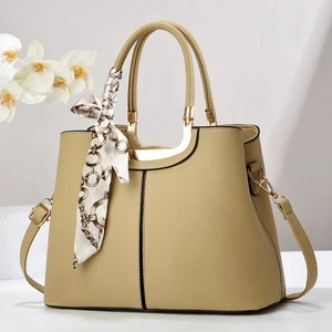 Detail of lychee pattern leather bag with gold handles and decorative silk scarf
