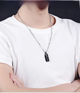 Detail of a men's black rectangular pendant with Love devotion text on a silver chain