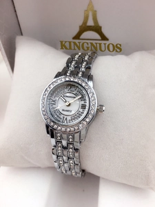 Detailed view of women's silver watch with rhinestone bezel and shell dial