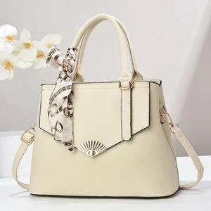 Detail of cream lychee texture tote bag featuring a gold fan buckle and silk scarf handle