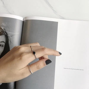 Detail shot of a silver star-pattern ring and an oval black onyx ring on a model hand