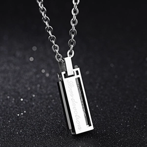 Polished stainless steel pendant necklace with Love devotion engraving on black bokeh background