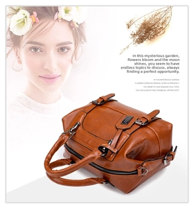 Detail of caramel crocodile pattern Boston bag with metal logo and sturdy handles