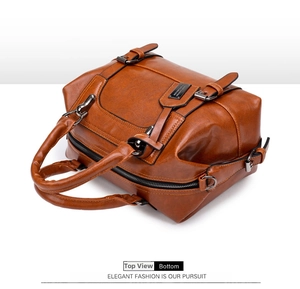 Top view detail of brown Boston bag showing crocodile texture and zipper closure