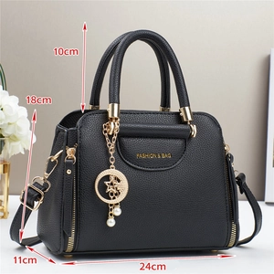 Detail view of black lychee leather bag with star moon pendant and pearl accents